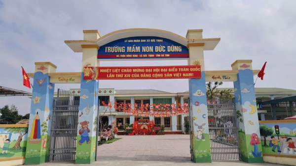 Cổng trường được trang trí cờ, khẩu hiệu, tạo không khí vui tươi, chào đón Đại hội XIV.